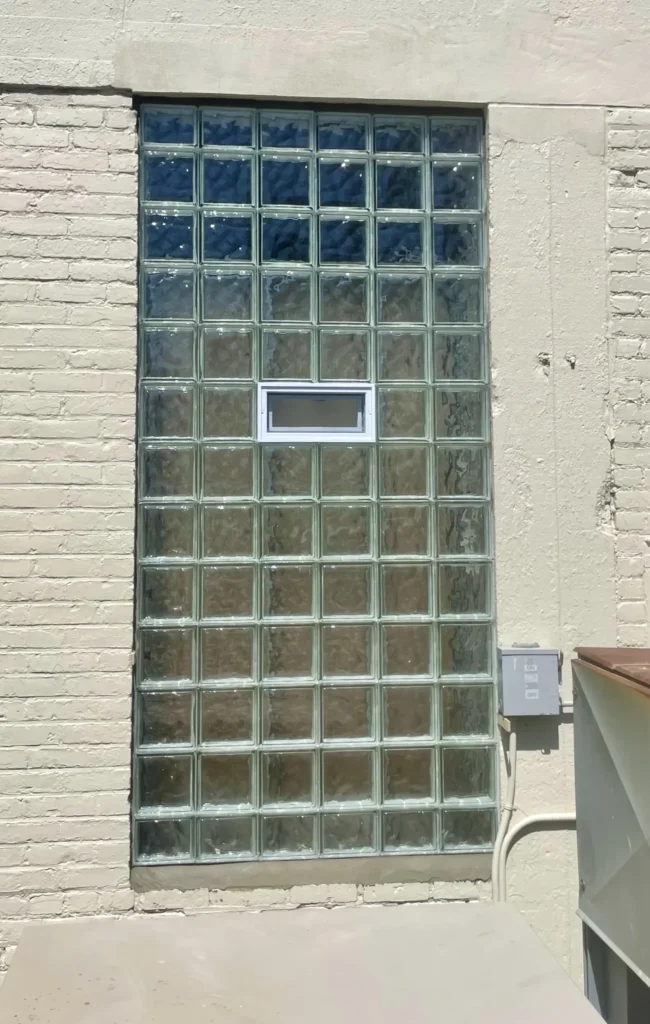Tall vented glass block window in painted brick wall